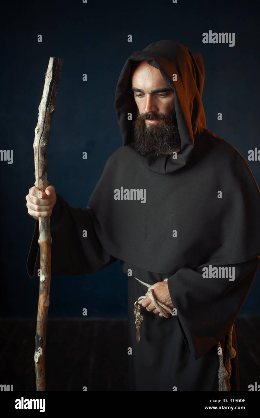 Moine médiéval en robe noire avec un capuchon repose sur un bâton, la  religion. Frère mystérieux dark cape Photo Stock - Alamy