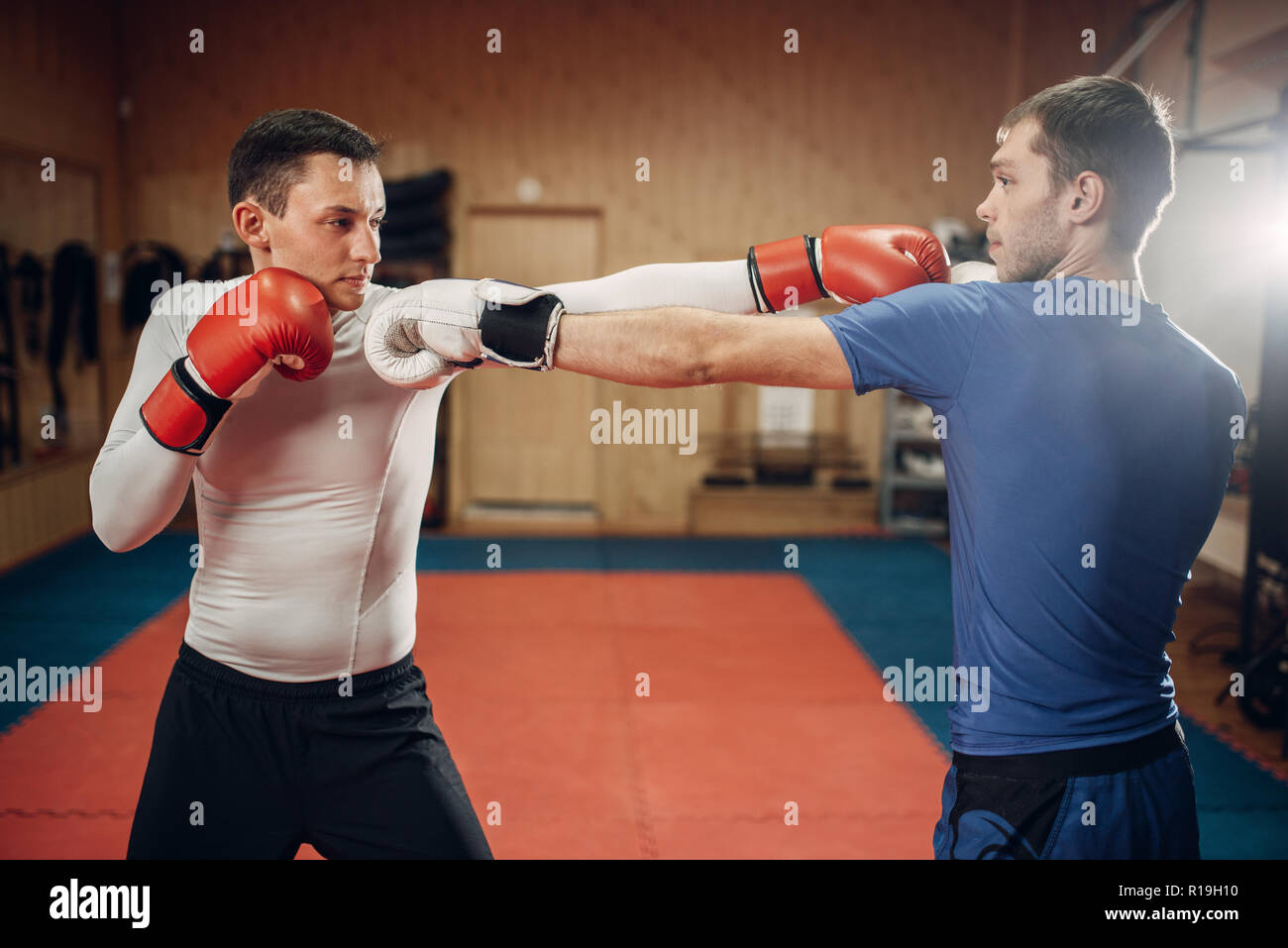 Deux hommes kickboxers dans la pratique sur les gants d'entraînement dans le gymnase. Fighters sur la formation, la pratique du kickboxing en action, sparring partners Banque D'Images
