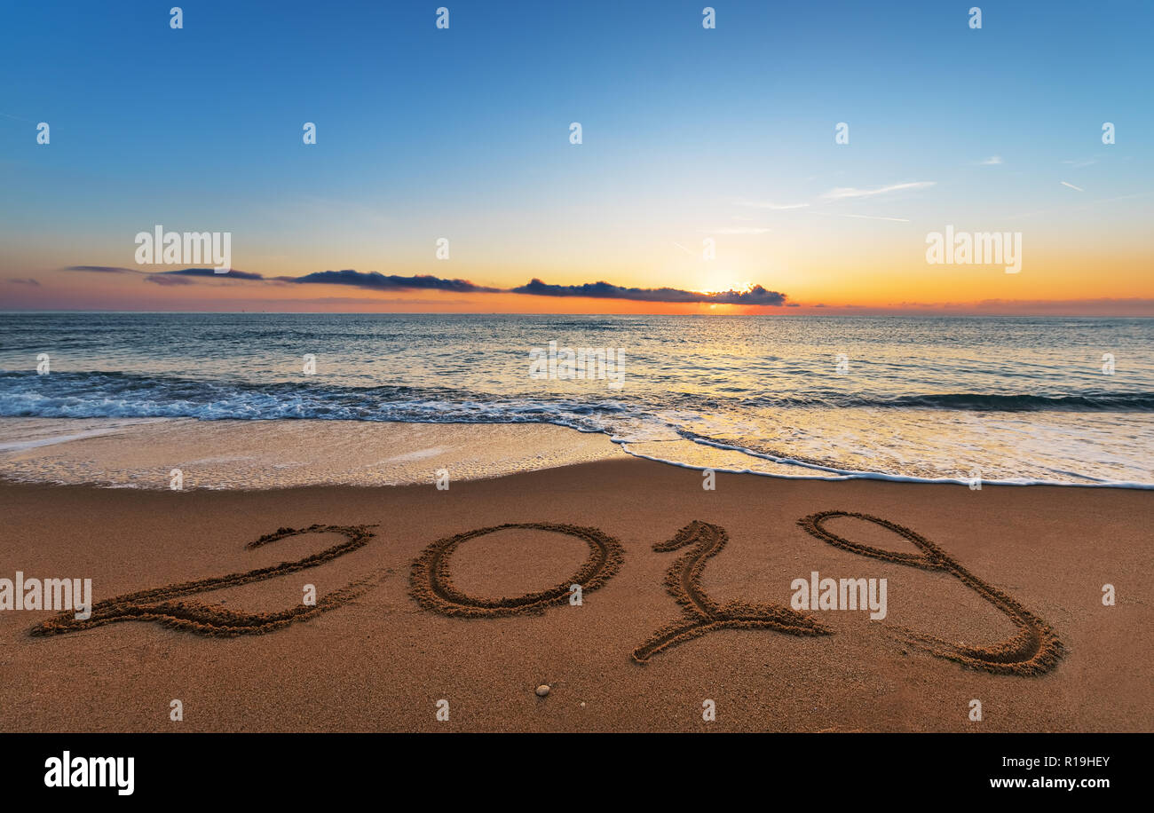 Nombre 2019 écrit sur le sable de mer au lever du soleil. Concept de la nouvelle année à venir et du temps qui passe. Banque D'Images