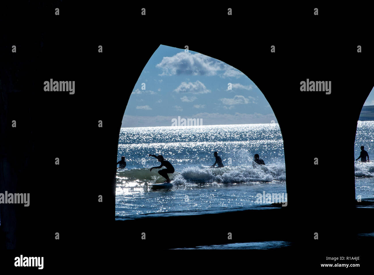 Surfers dans la mer sur la plage de Bournemouth en plein été, en dessous de la célèbre jetée Banque D'Images