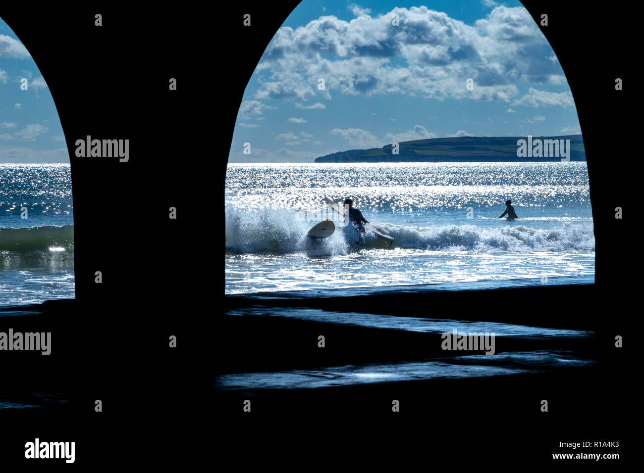 Surfers dans la mer sur la plage de Bournemouth en plein été, en dessous de la célèbre jetée Banque D'Images