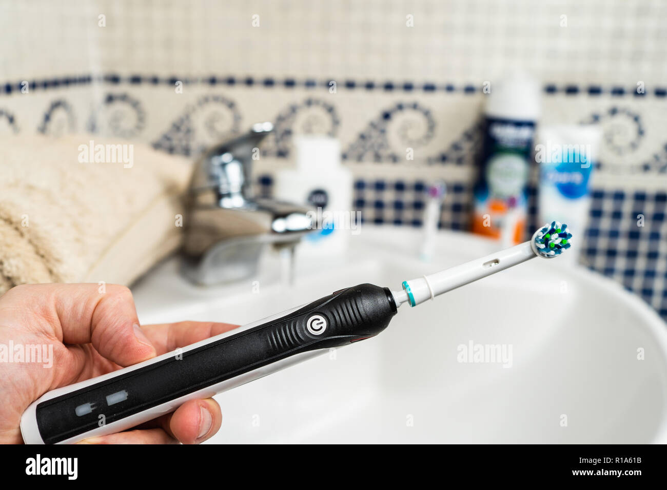 Brosse à dents electrique rechargeable avec une poignée noire et cinq têtes de brosse à dents.fond bleu clair. Banque D'Images