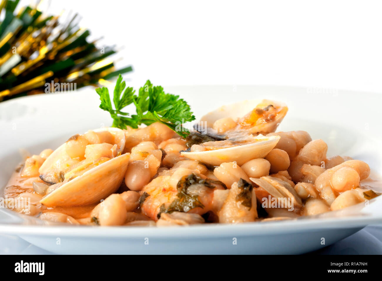 Une assiette de haricots blancs aux palourdes et langoustines et décoration de Noël isolé sur blanc. Banque D'Images