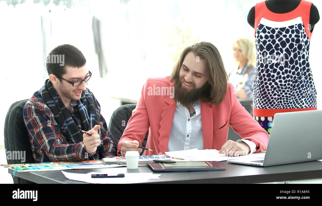 Deux concepteurs créatifs discuter de nouvelles idées assis à une table dans un studio de création Banque D'Images