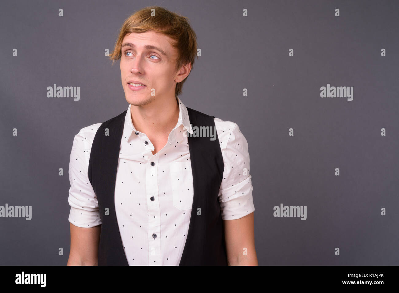 Beau jeune homme aux cheveux blonds contre gray backgrou Banque D'Images