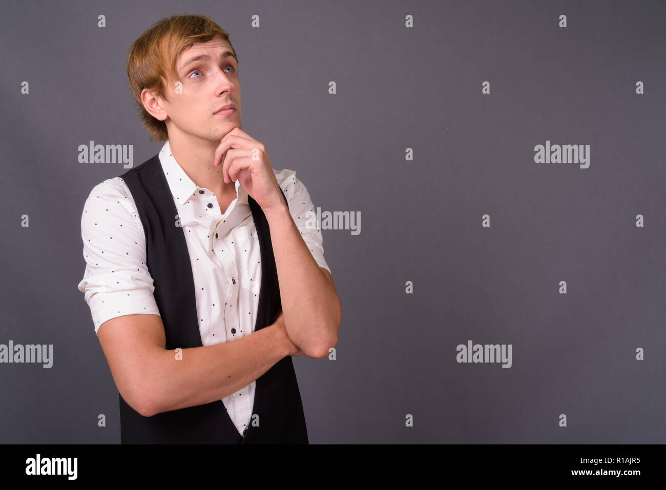 Beau jeune homme aux cheveux blonds contre gray backgrou Banque D'Images