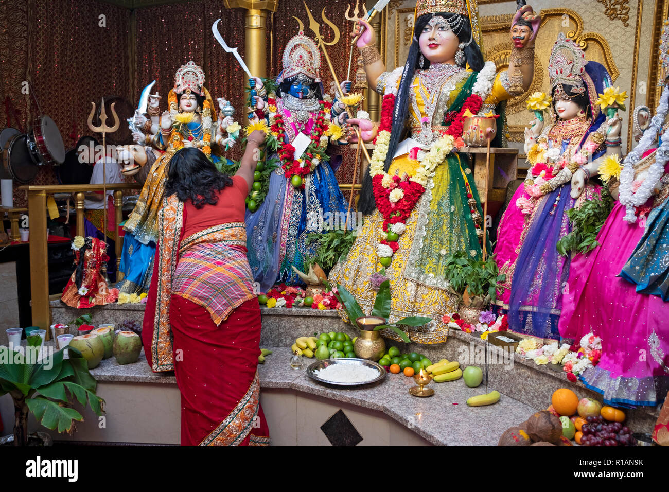 Un hindou dévot porte les fleurs à la déesse Kali dans un temple hindou de Shakti dans le Queens, New York. Banque D'Images