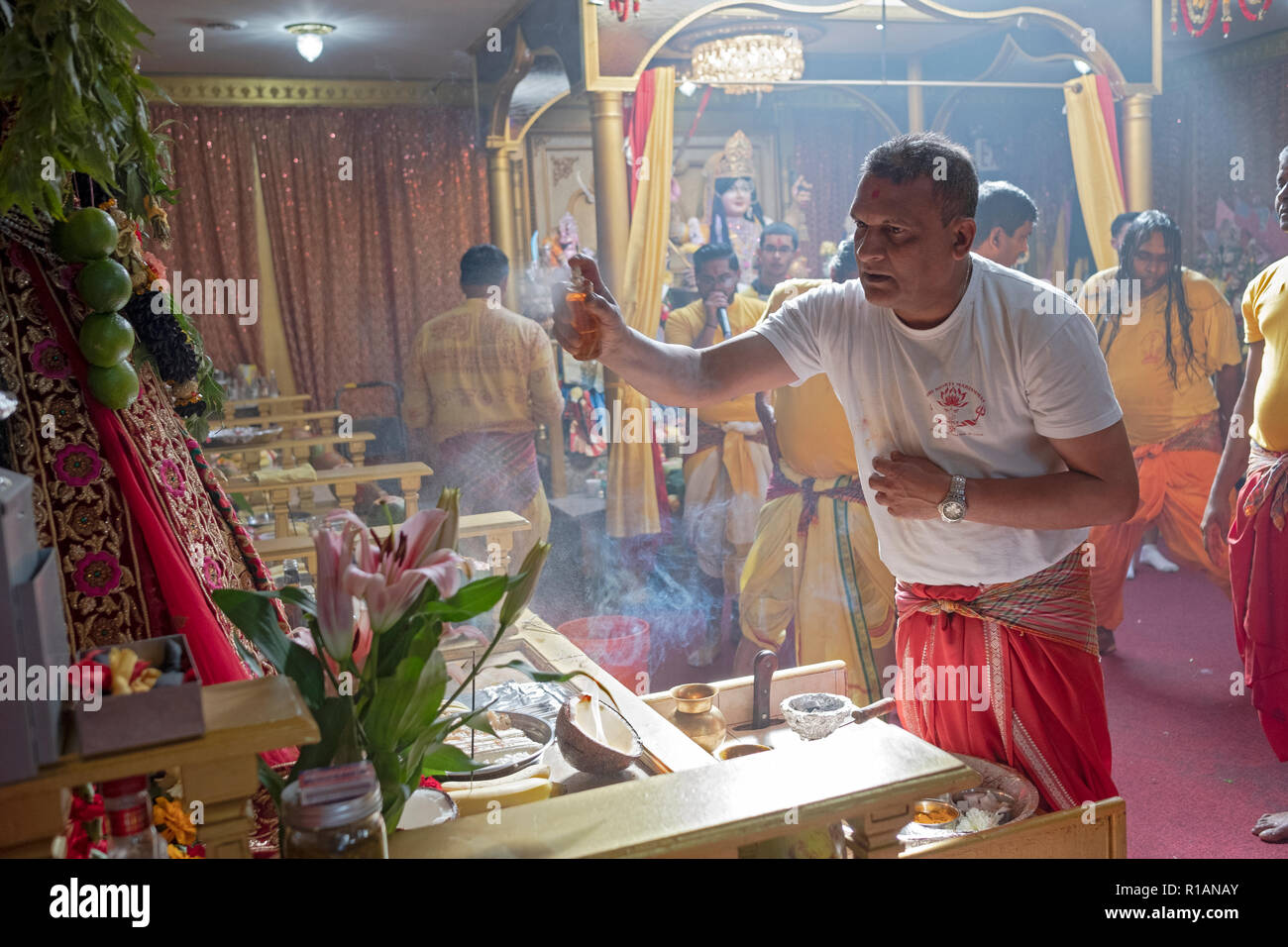 Un dévot hindou parfum vaporisateurs sur une statue de la déesse Kali à un temple hindou Shakti dans le Queens, New York. Banque D'Images