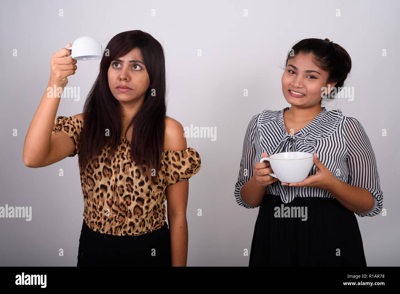 Studio shot of young woman holding perse la tasse de café vide upsi Banque D'Images