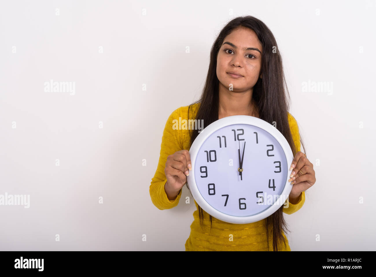 Studio shot of young woman holding montrant l'horloge murale Banque D'Images