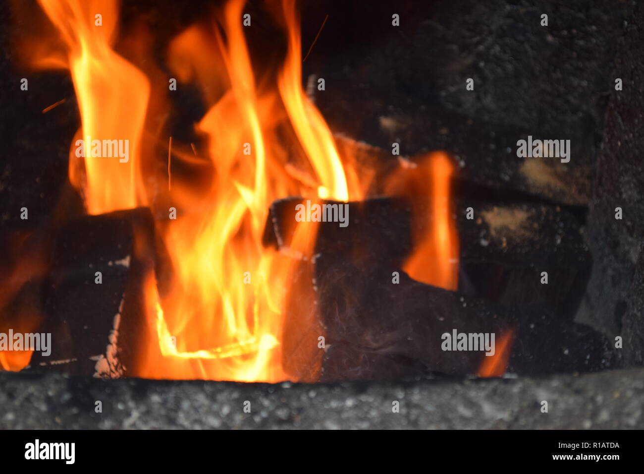 Close up of Brown les briquettes de charbon en feu avec flammes jaunes rouge à l'intérieur d'un four spécial, solide rouge et orange texture floue sur un fond noir. Banque D'Images