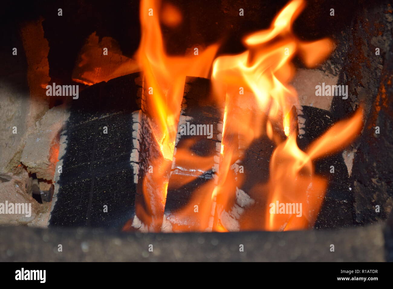 Close up of Brown les briquettes de charbon en feu avec flammes jaunes rouge à l'intérieur d'un four spécial, solide rouge et orange texture floue sur un fond noir. Banque D'Images