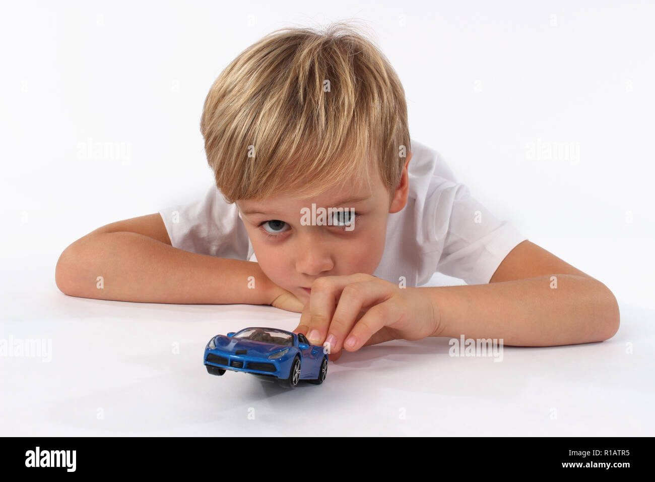 Cute blonde yeux bleu petit Garçon jouant avec des jouets de voiture Banque D'Images