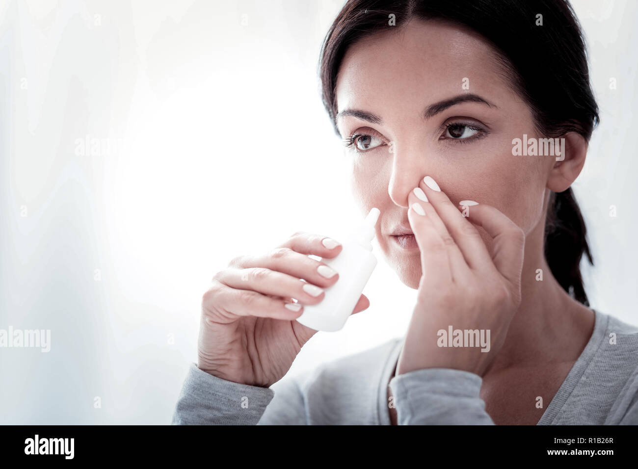 Portrait de jeune femme en utilisant des gouttes Banque D'Images