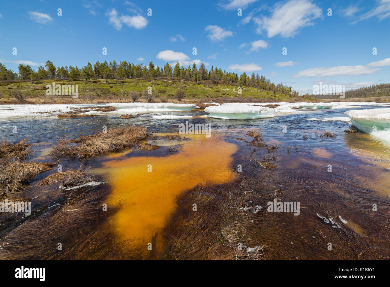 Paysage de printemps sur le ruisseau aux eaux turquoises des banquises de glace sous-marine, orange et vertes collines sur un beau jour dans le sud de la Iakoutie, Russie Banque D'Images
