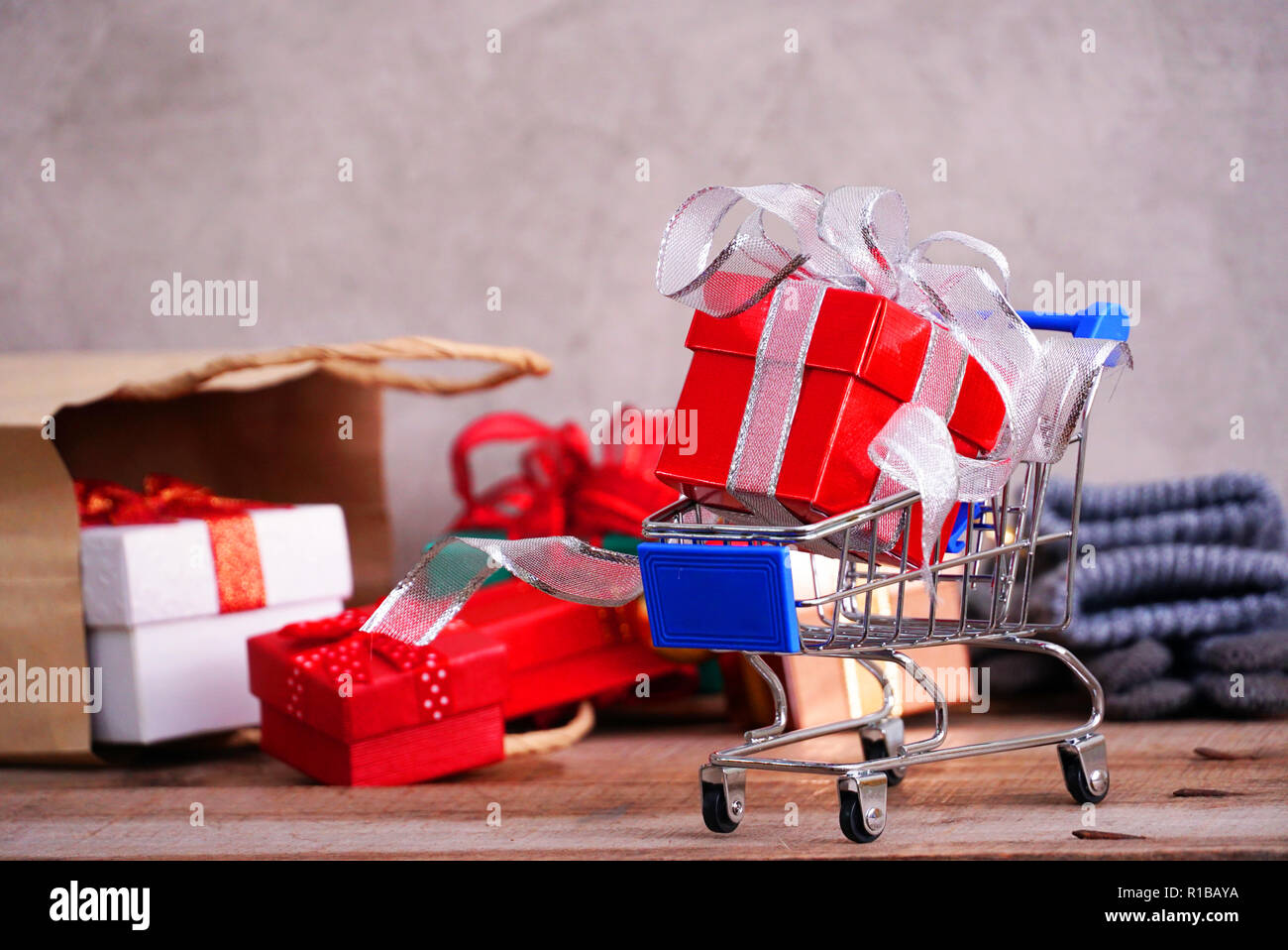 Boîte cadeau rouge sur fond de panier de petites boîtes cadeaux débordent de sac de papier, shopping concept. Banque D'Images