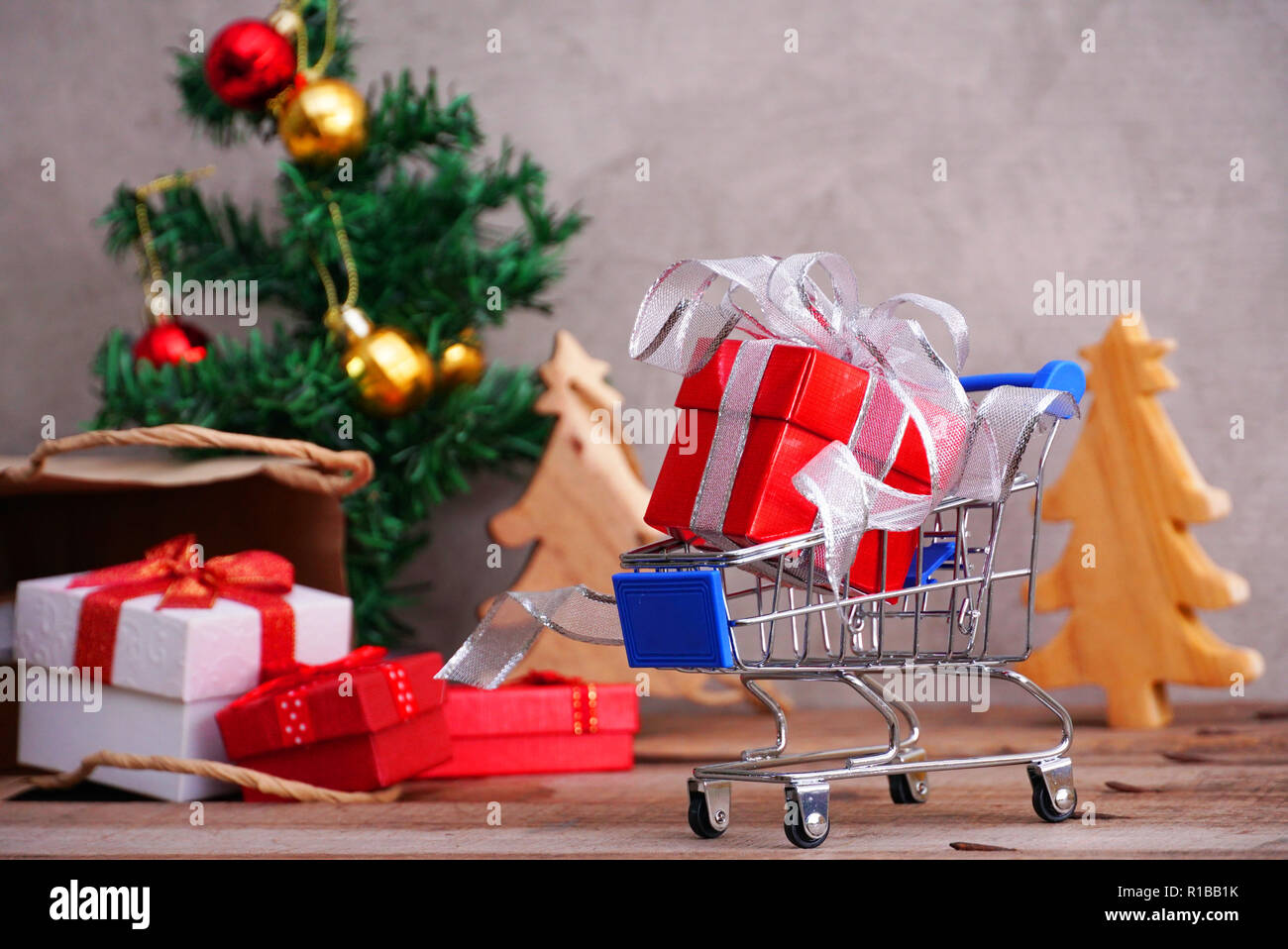Boîte cadeau rouge sur fond de panier de petites boîtes cadeaux débordent de sac en papier et christmad arbre pour shopping concept. Banque D'Images