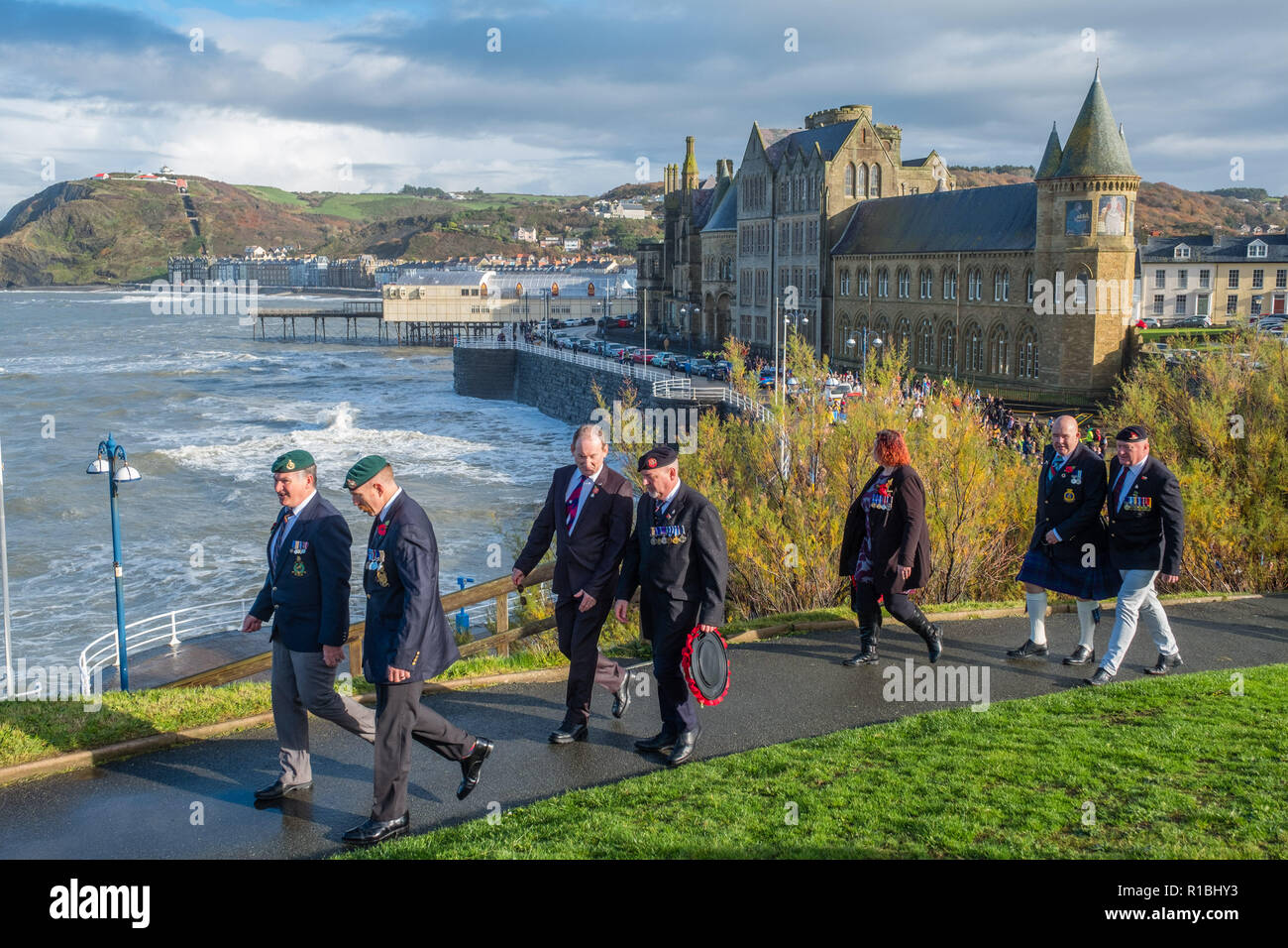 Pays de Galles Aberystwyth UK, 11/11/2018. Les gens se réunir pour déposer des couronnes et d'hommage aux soldats tombés dans toutes les guerres et les conflits, le Dimanche du souvenir, et le 100e anniversaire de l'Armistice qui mit fin à la Première Guerre mondiale, dans des conditions très venteuses mais lumineux à l'emblématique monument commémoratif de guerre dans le château pointe à Aberystwyth sur les côtes de la Baie de Cardigan, West Wales crédit photo Keith Morris / Alamy Live News Banque D'Images