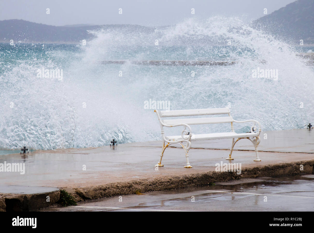 Banc vide par la mer agitée éclaboussé par la vague en Dalmatie ville balnéaire en hors saison au cours de Vent du sud fort Banque D'Images