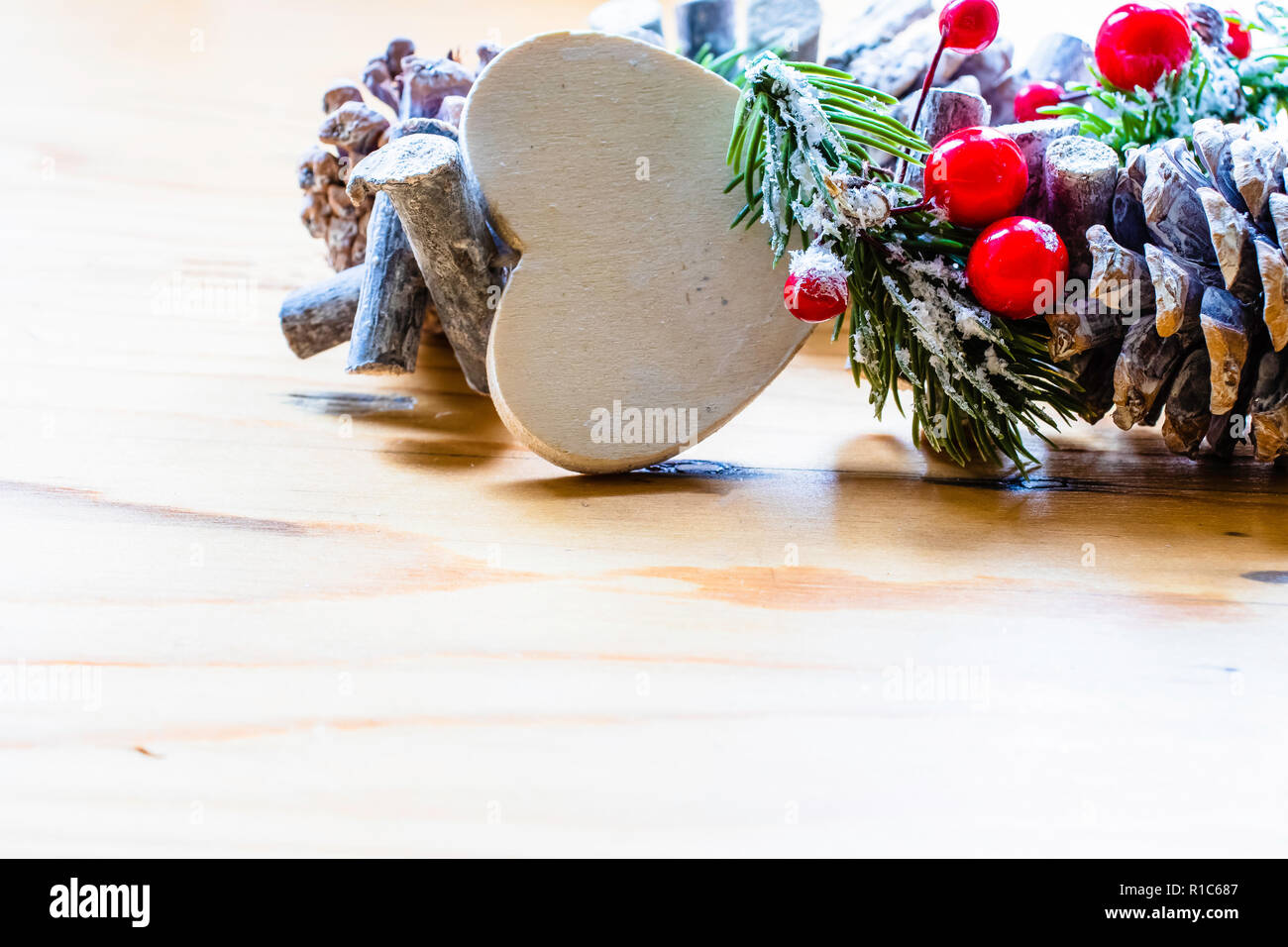 Couronne de Noël scandinave avec des baies rouges et des pommes de pin sur une table en bois clair Banque D'Images