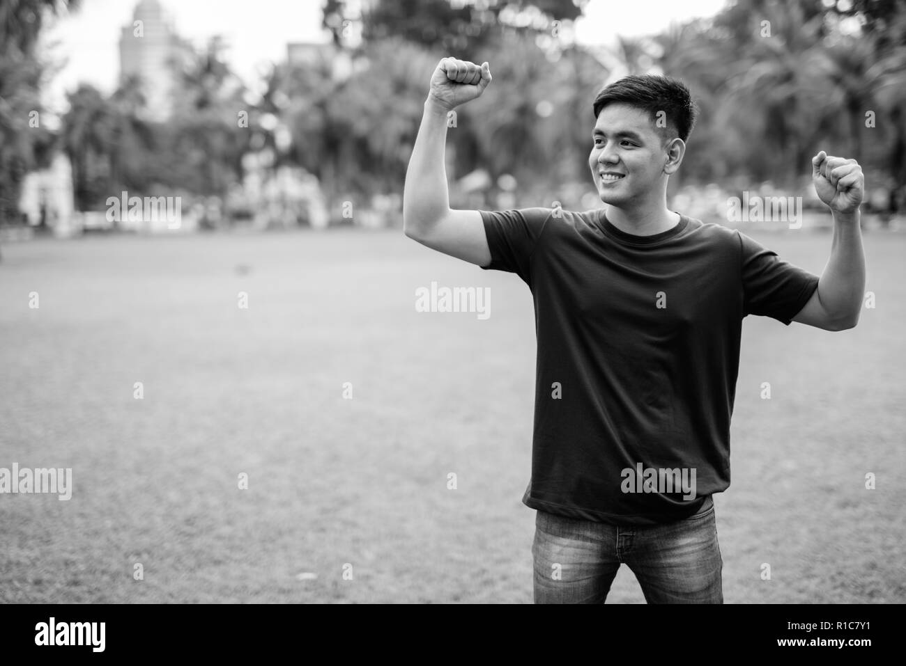 Beau jeune homme asiatique se détendre au parc avec des bras levés Banque D'Images