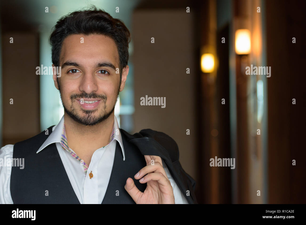 Young happy Indian man smiling while holding veste dans les corri Banque D'Images