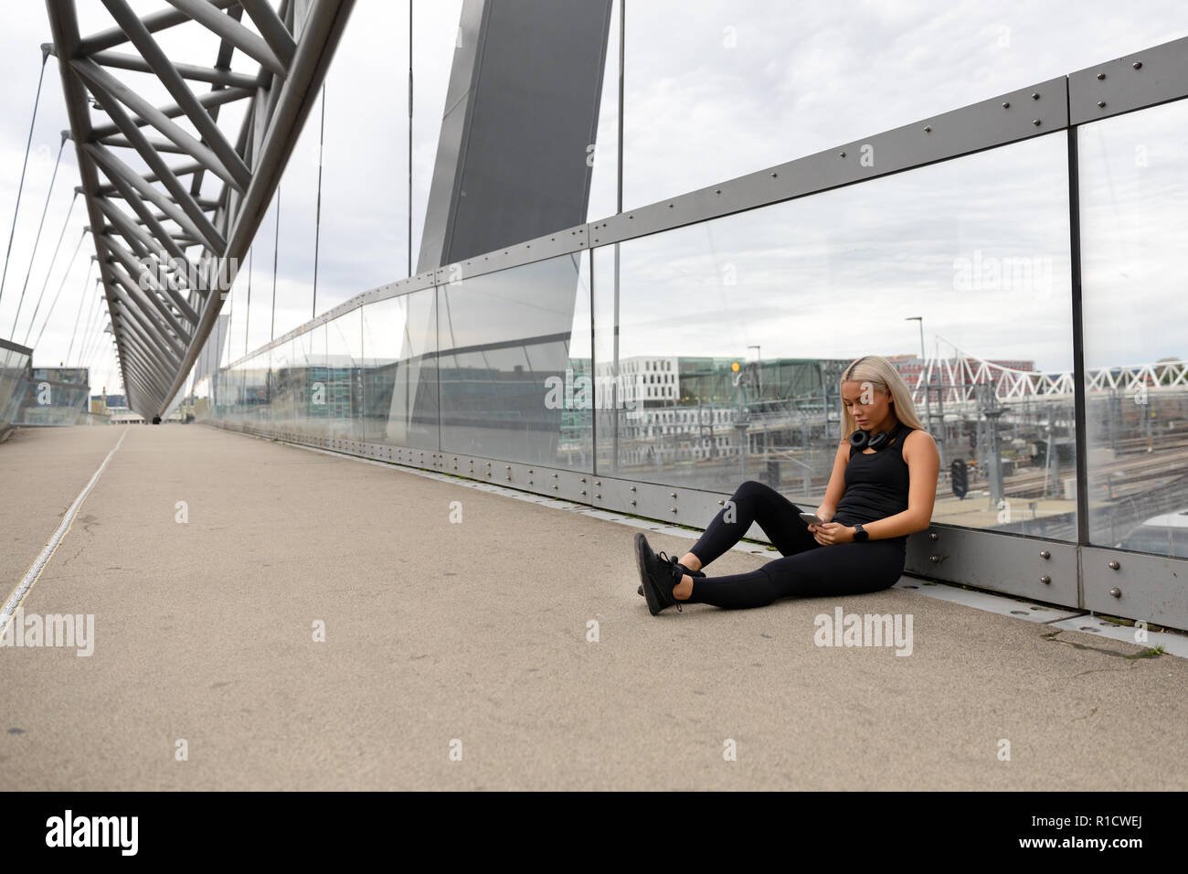 Runner assis sur Bridge après entraînement et l'utilisation de Smart Phone Banque D'Images