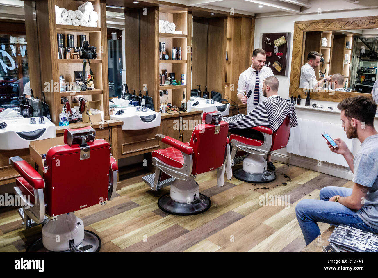 Londres Angleterre,Royaume-Uni,South Bank Southwark,Borough Market,The Groomsmith,barbershop,man men male,barber,client,attente,coupe de cheveux,en utilisant smartphone,chaise,in Banque D'Images