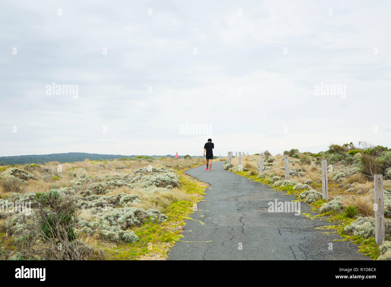 Homme seul s'exécutant sur un chemin vide, loin de l'appareil photo. Banque D'Images