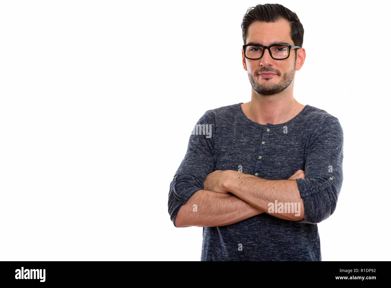 Studio shot of young man wearing eyeglasses with arms c Banque D'Images