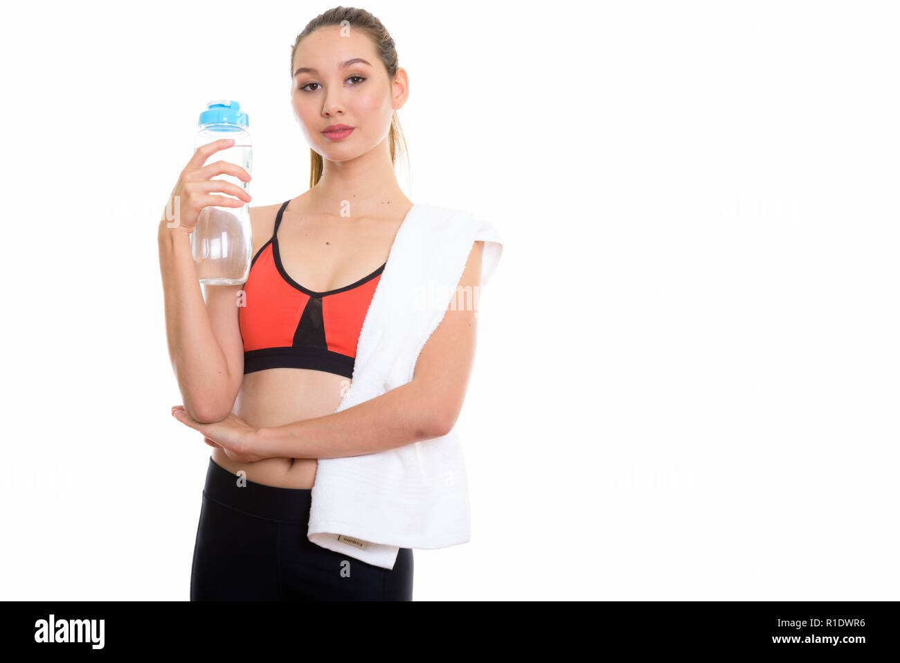 Studio shot of young beautiful Asian woman holding water bottle Banque D'Images