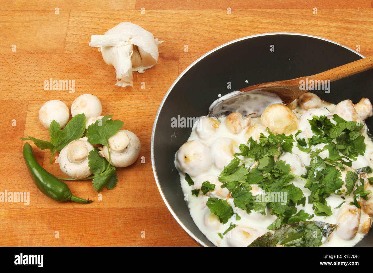 Libre de Balti de champignons dans une casserole avec les ingrédients sur un plan de travail en bois Banque D'Images