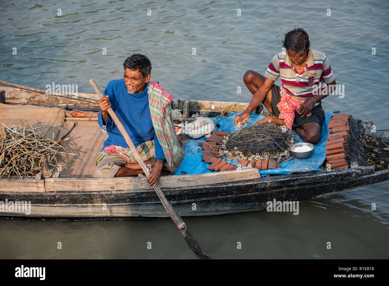 Le tri des pêcheurs leur attirail de pêche sur leur bateau sur un matin ensoleillé dans les Sundarbans, West Bengal, India Banque D'Images