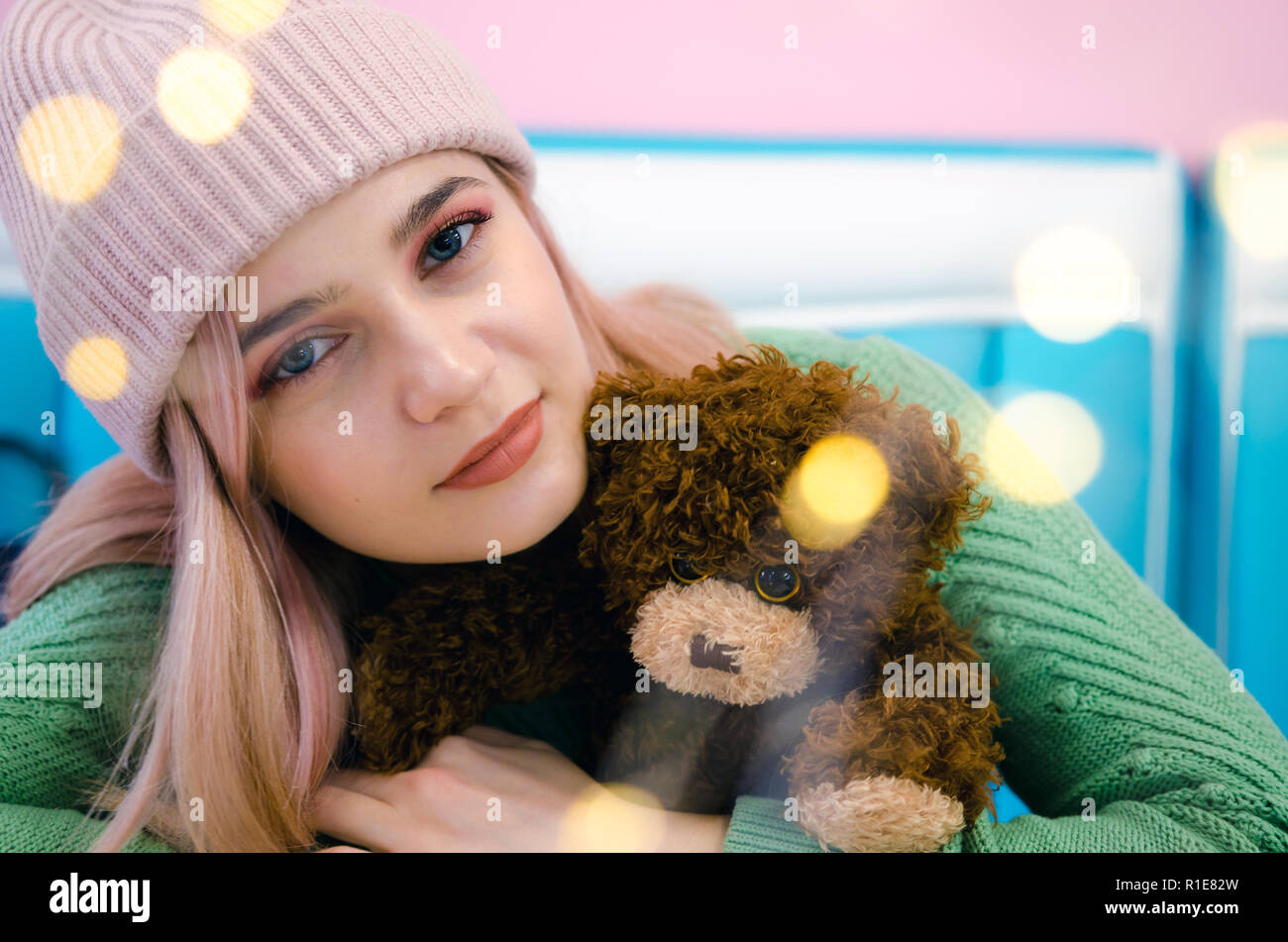 Portrait d'une jolie fille en pull vert. Femme avec ours Taddy. Lumières Bokeh Banque D'Images