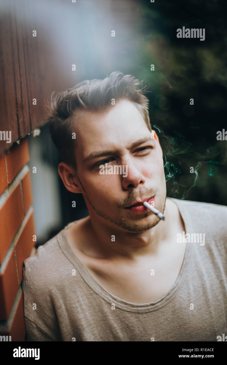 Photo d'un visage d'un jeune homme qui fume une cigarette Banque D'Images