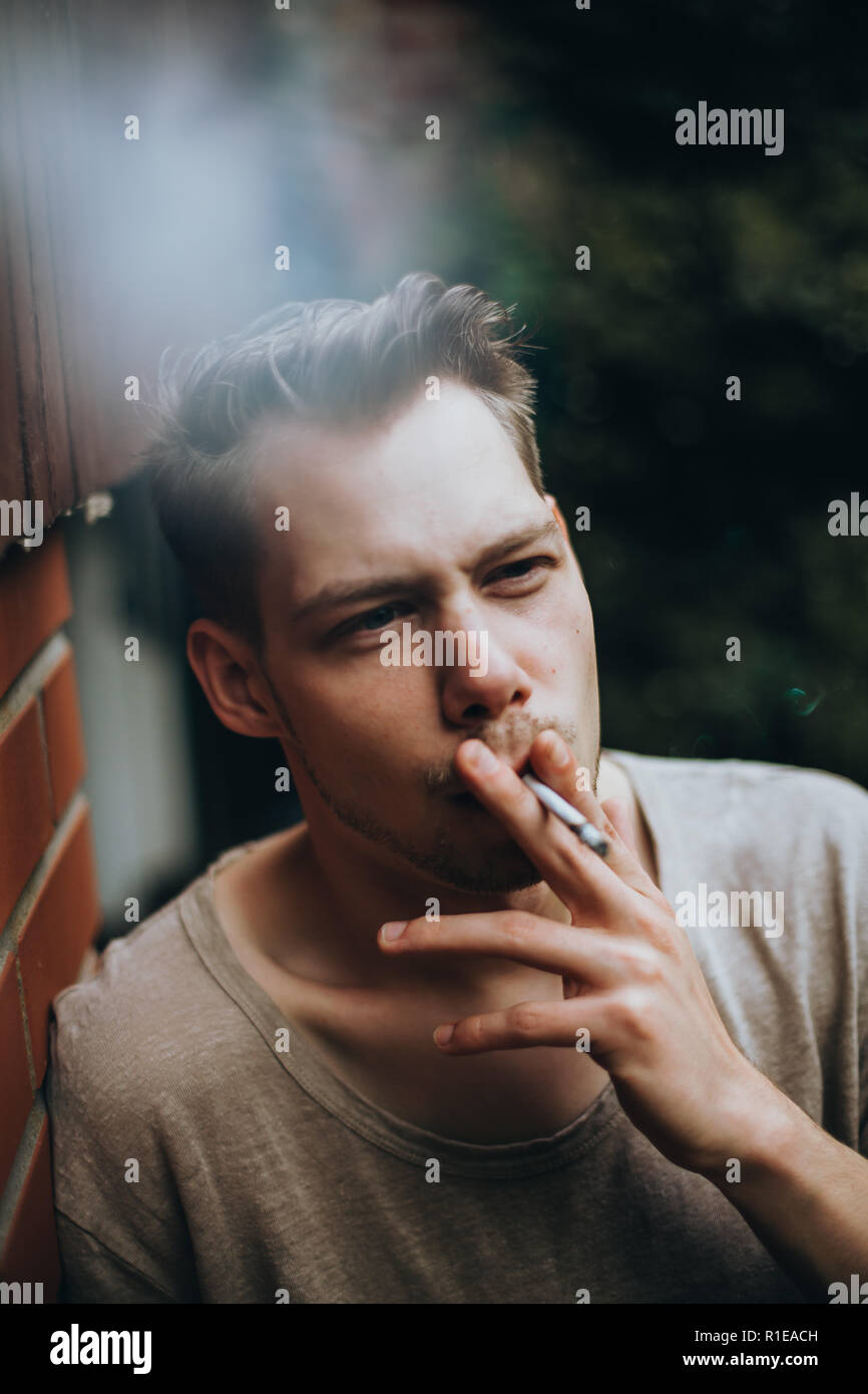 Photo d'un visage d'un jeune homme qui fume une cigarette Banque D'Images