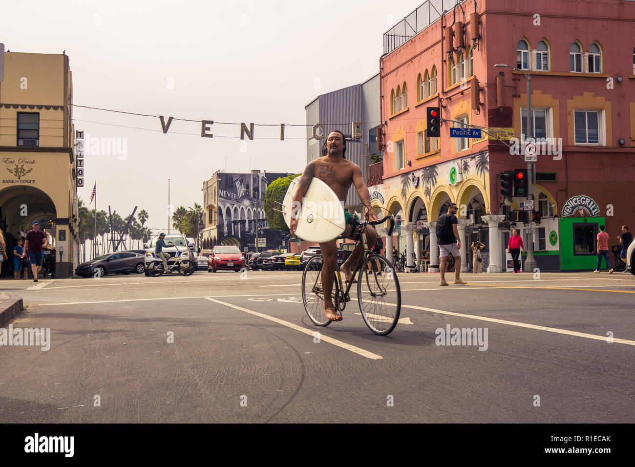 Un internaute de retour à la maison sur son vélo with surfboard at Venice Beach, Los Angeles, Californie Banque D'Images