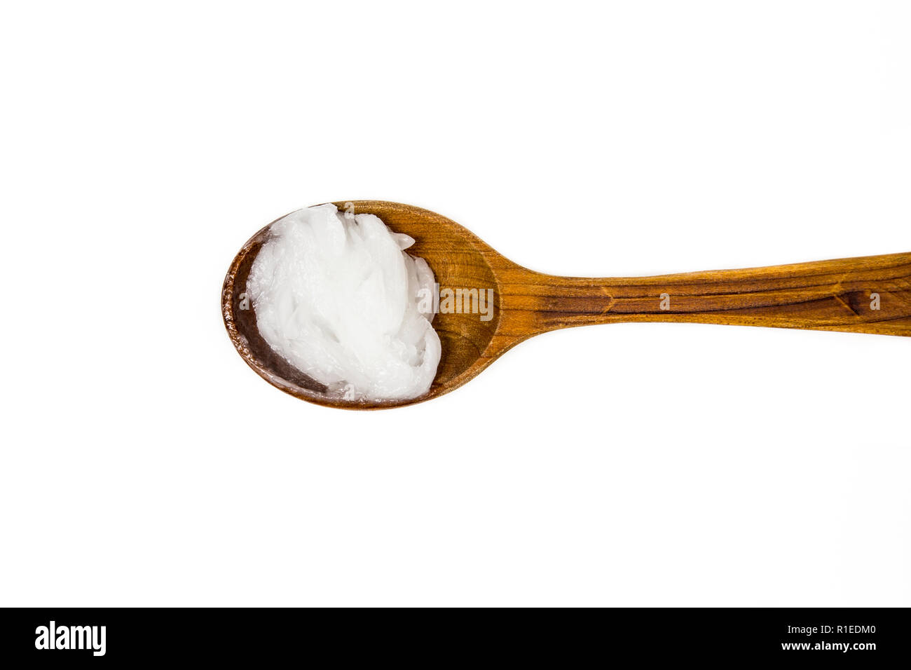 L'huile de coco vierge solide ou de l'huile de coprah, est une huile comestible. Sur brown cuillère en bois isolé sur blanc. Pour remplacer les crèmes boutique concept. Banque D'Images