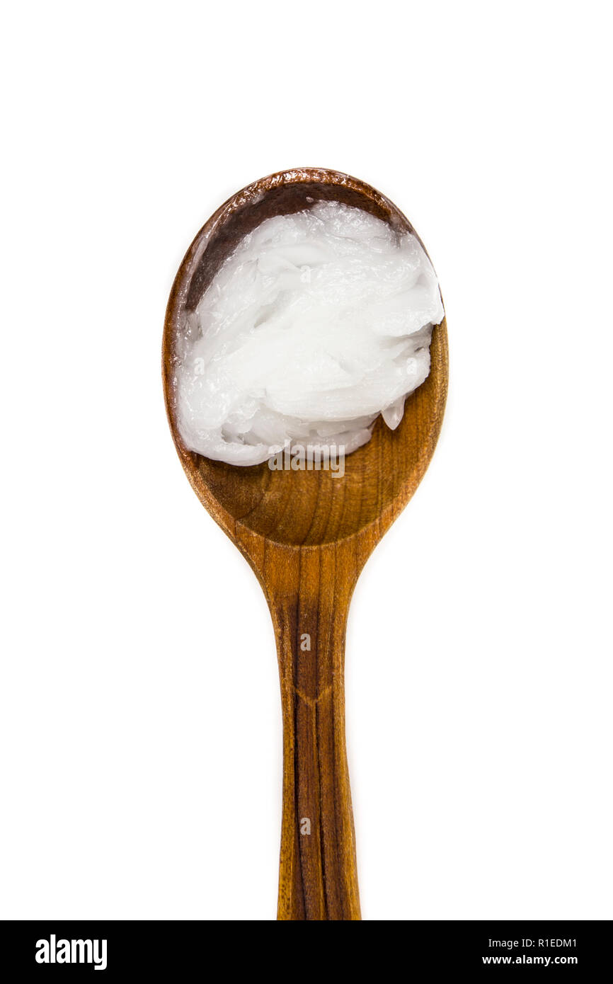 L'huile de coco vierge solide ou de l'huile de coprah, est une huile comestible. Sur brown cuillère en bois isolé sur blanc. Pour remplacer les crèmes boutique concept. Banque D'Images