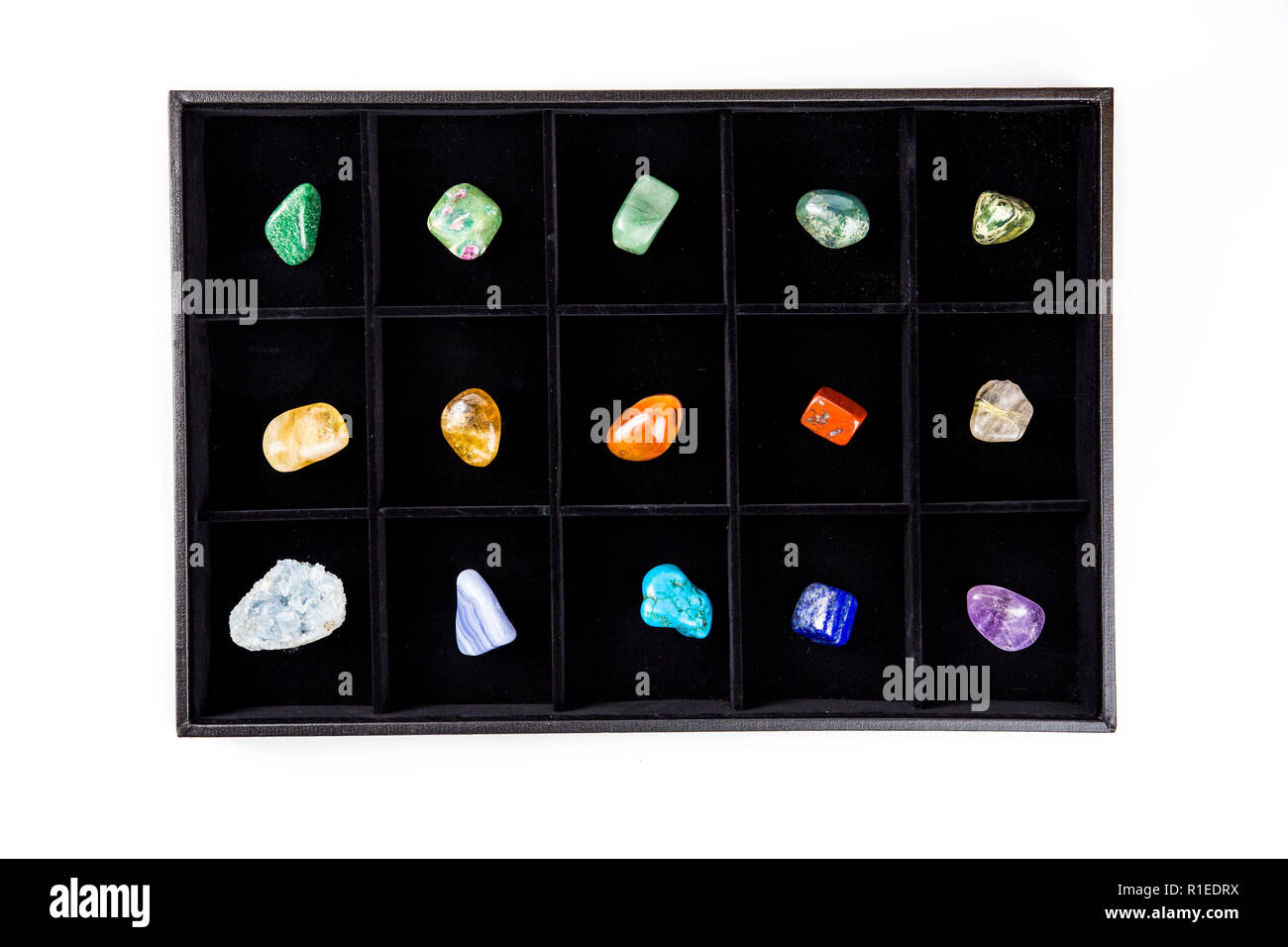 Mise à plat de la variété de pierres semi-précieuses colorées cristaux dans organiser box triées par isolé sur la couleur noire. Banque D'Images
