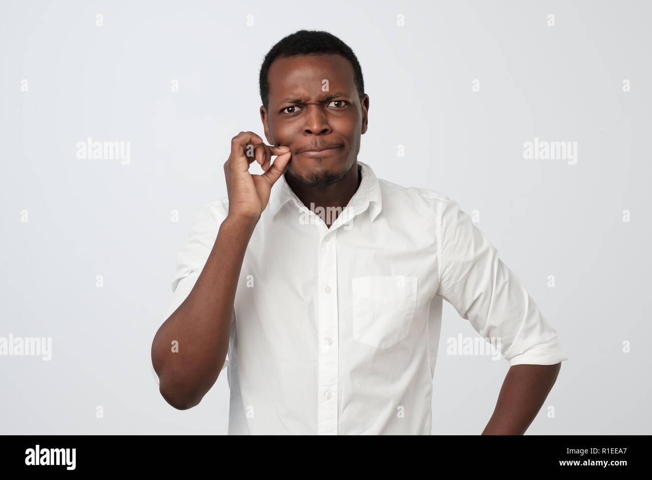 Bel homme africain montrant un signe de fermer la bouche et le silence. Je le garde en secret Banque D'Images