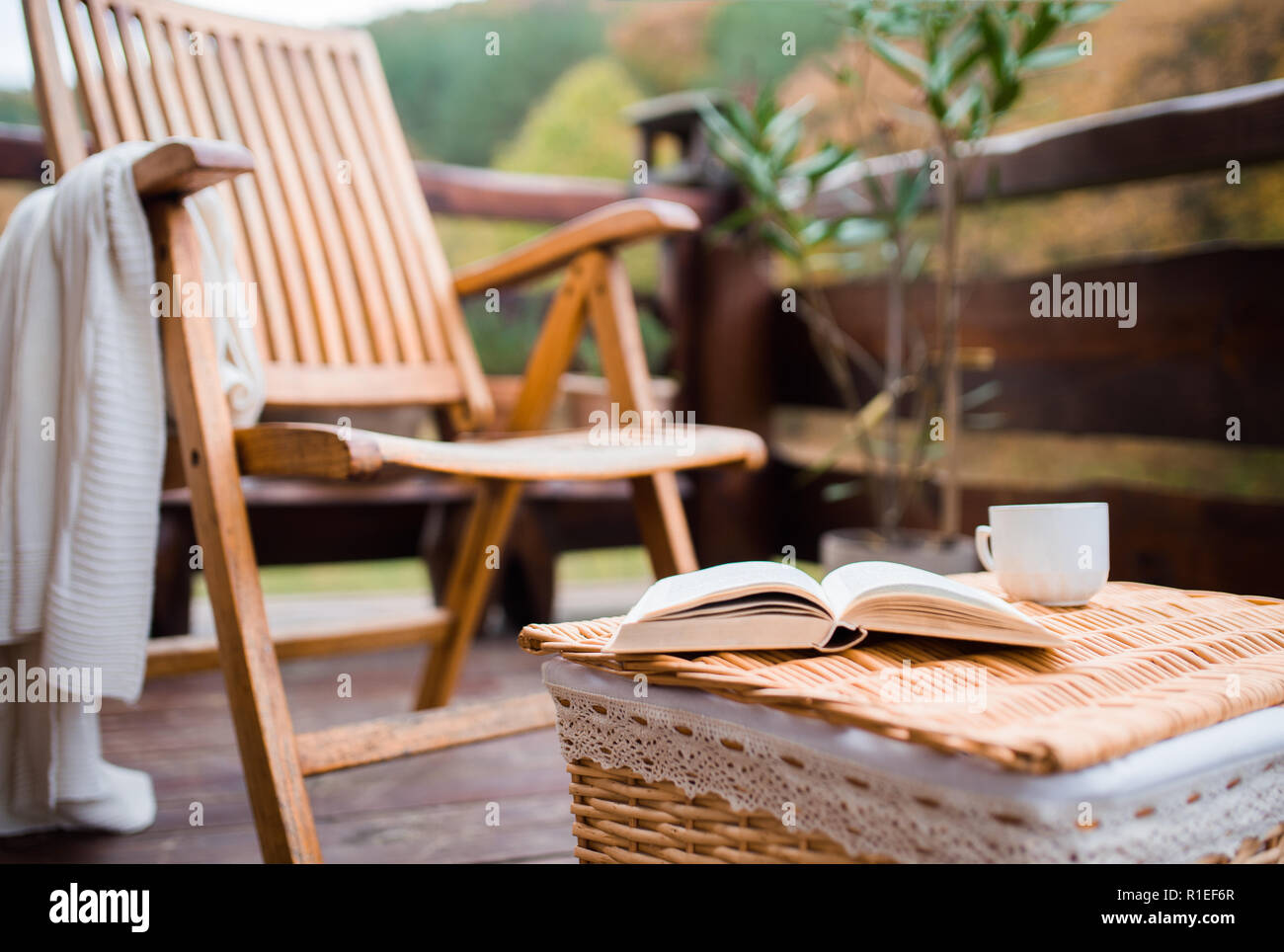 Une chaise en bois et un livre sur un panier sur une terrasse sur une journée ensoleillée à l'automne. Banque D'Images
