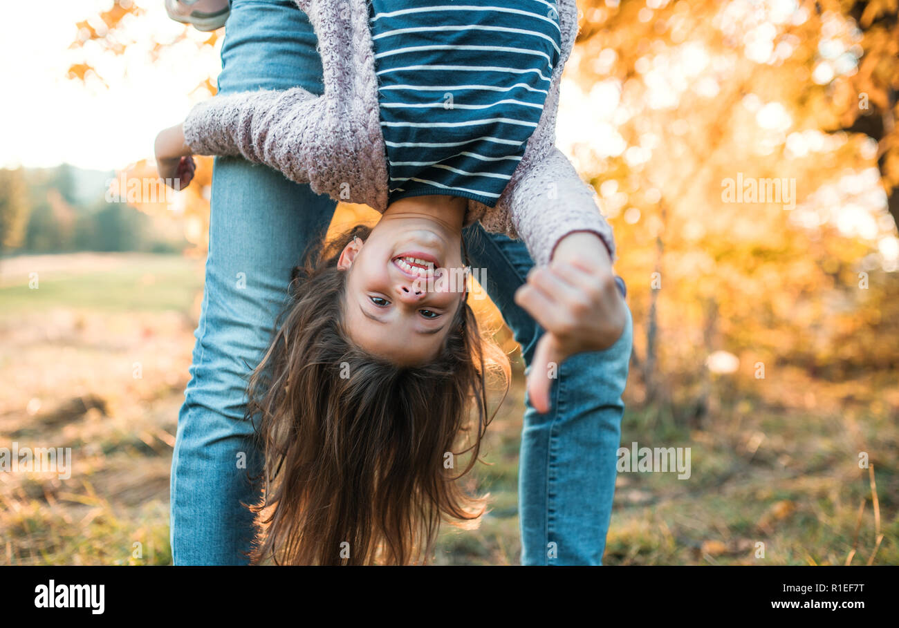 Un père tenant une petite fille à l'envers à l'automne la nature. Banque D'Images