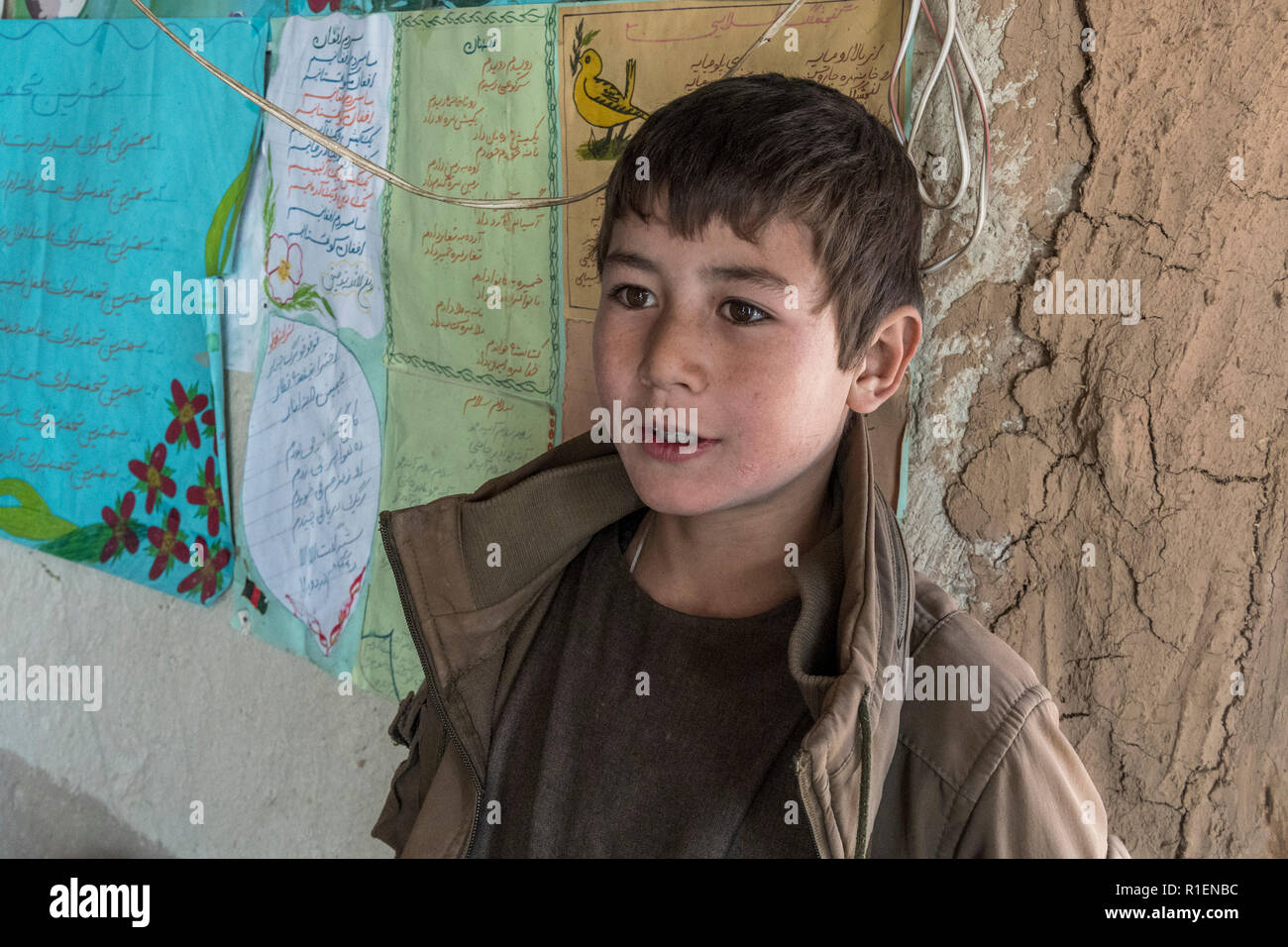 Boy est enseigné en anglais par Enseignante en Co-Educational School Situé à Hillside village troglodyte, province de Bamyan, Afghanistan Banque D'Images