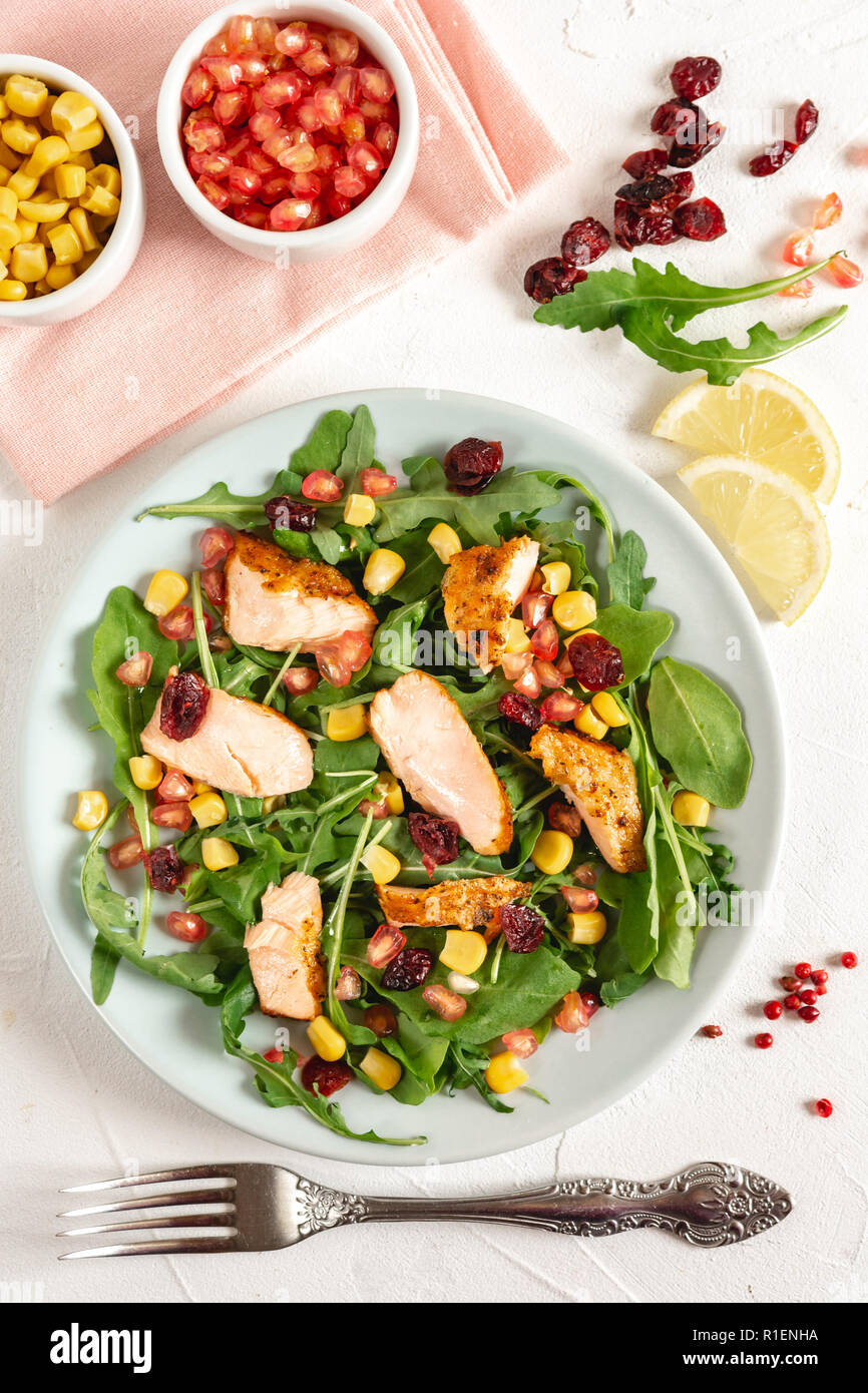 Salade avec du saumon grillé, roquette, de maïs, de grenade et canneberge saupoudrée de citron et huile d'olive. Banque D'Images