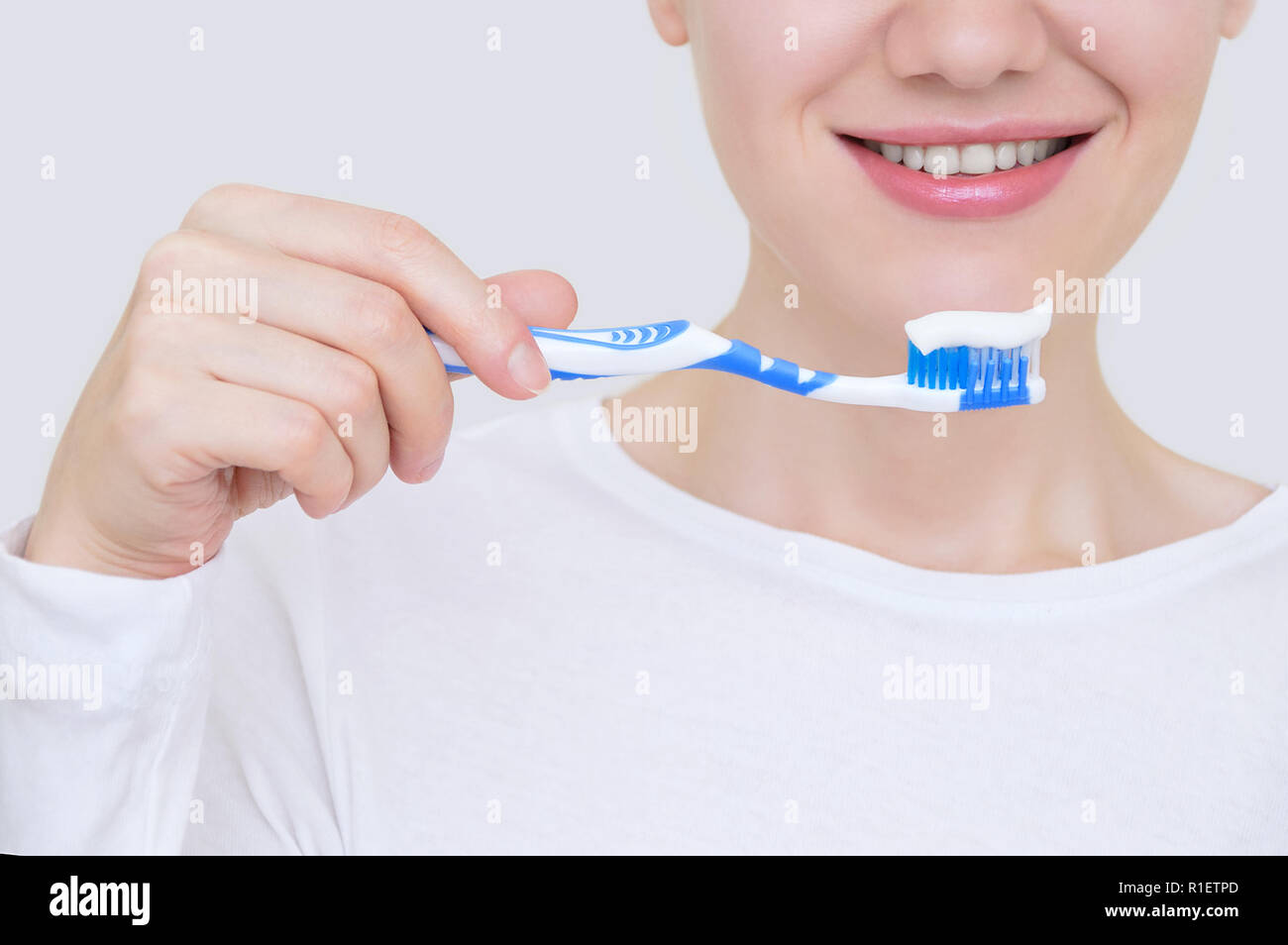 Fille avec une brosse à dents avec des pâtes dans la main en souriant. Close-up. Banque D'Images