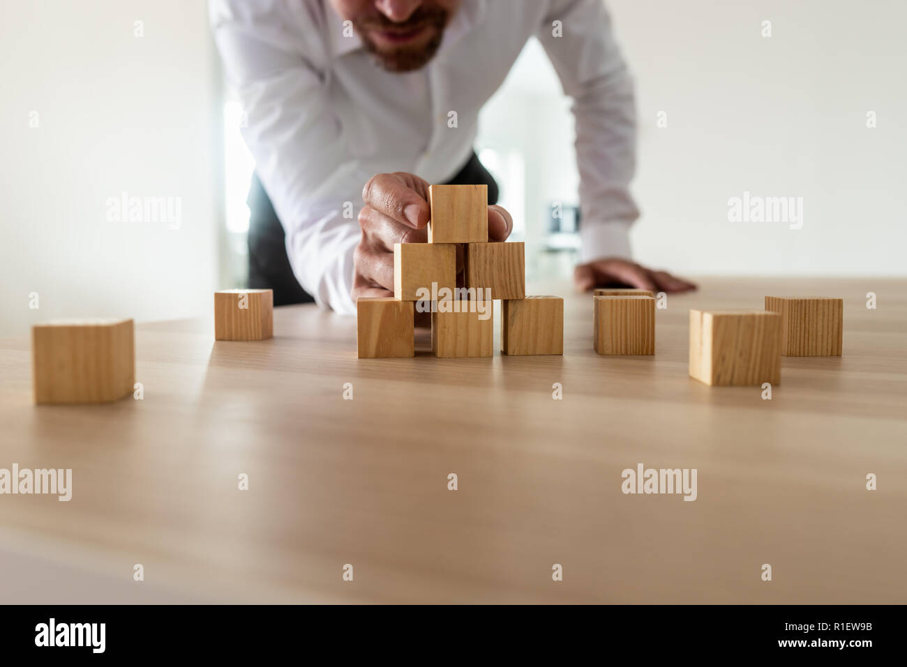 Businessman leaning à monter avec pyramide avec blocs de bois vierge sur office 24. Démarrage d'une entreprise de conception et de vision. Banque D'Images