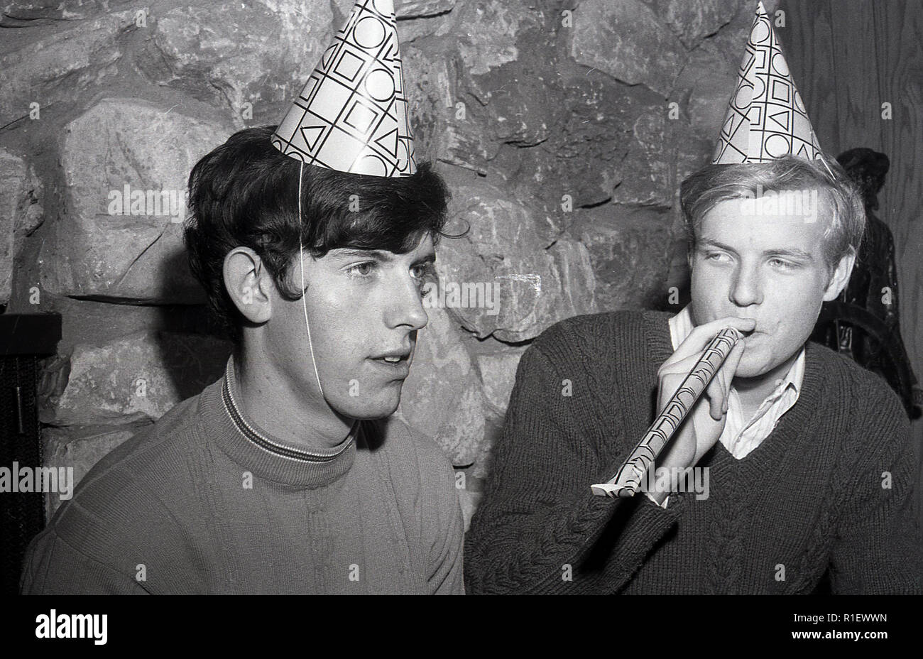 Années 1970, historiques, une partie, LA, deux jeunes hommes portant des chapeaux de fête ou de cônes sur la tête, un souffle un streamer papier, Los Angeles, USA. Banque D'Images