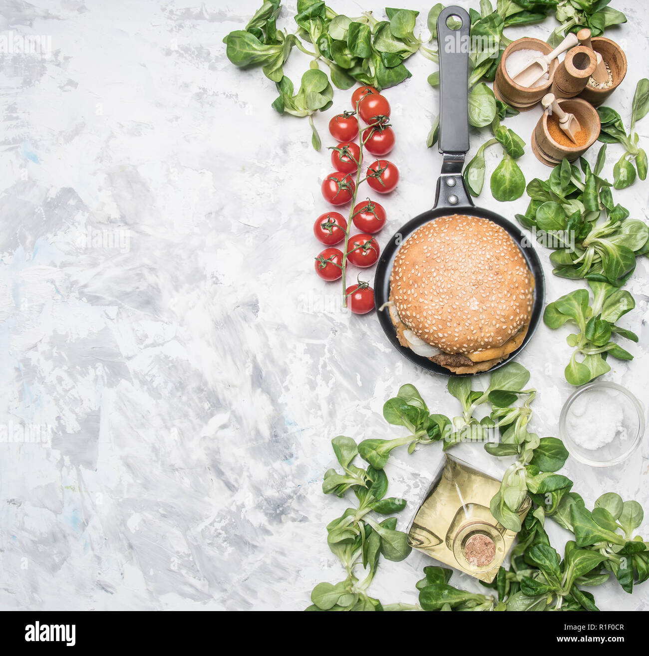 Une cuisine avec du poulet burger fait maison, et d'une escalope salade de salade avec des tomates cerises, les assaisonnements et l'huile, sur un arrière-plan blanc vintage rustique Banque D'Images