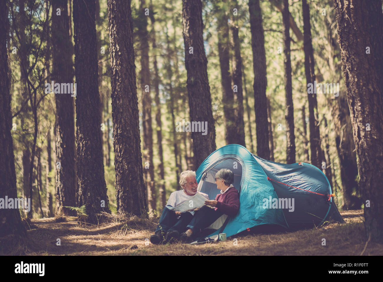 Couple de personnes adultes senior caucasian n liberté camping dans une forêt de pins sous haute avec une tente en alternative sauvages voyage vacances à li Banque D'Images